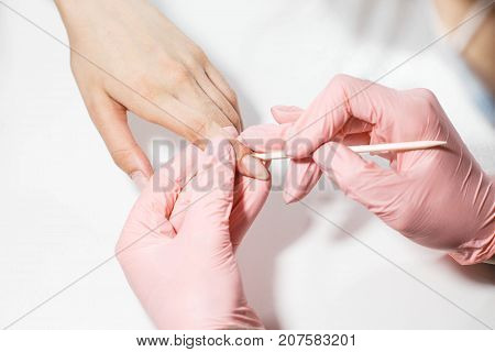 The master does a manicure to a girl. Close-up on a white background.