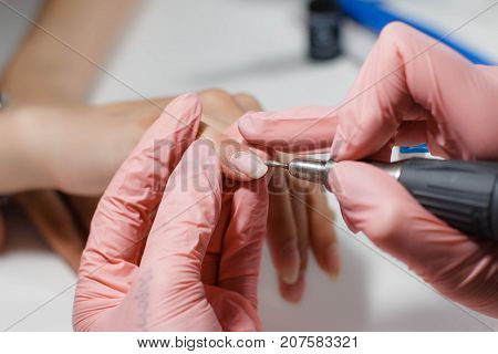 Hardware manicure. Removal of old gel varnish in the salon. Manicure master doing beauty procedure for client, closeup and top view