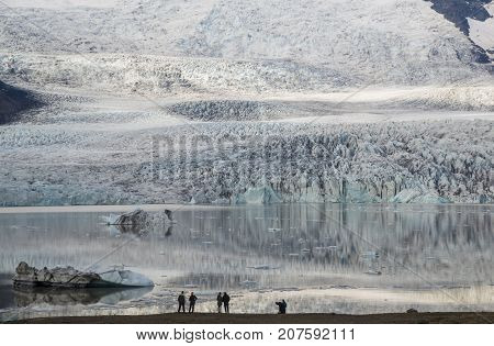 Several people contemplate Ice Lagoon Fjallsarlon. Glacier of this lagoon is just a short distance away view point.