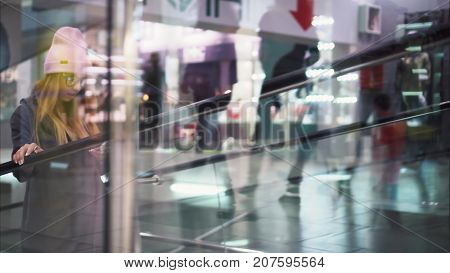 A young stylish hipster woman climbs a trevalator in a store. Shopping