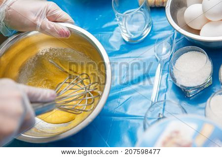 Whipping eggs. Chef hands close-up whisk eggs on a black background. Natural light slightly toned image. Close-upView