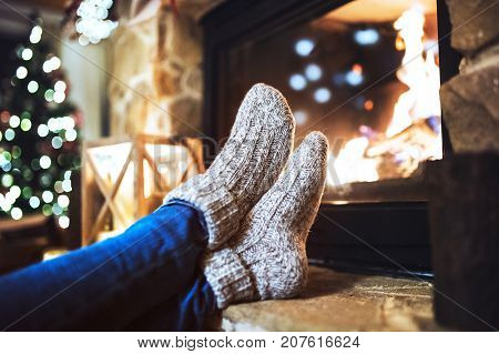 Feet of unrecognizable woman sitting in front of the fireplace, resting. Christmas time.