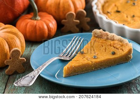 Healthy dessert for Thanksgiving. Pumpkin open pie with pumpkin seeds served with small decorative pumpkins and wholegrain gingerman cookies closeup