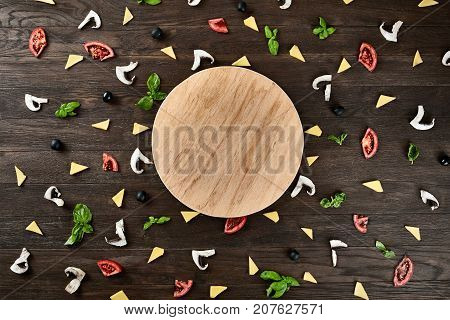 Four cheese pizza quattro fromaggi on a rustic wooden board on the table with ingridients. Selective fovus