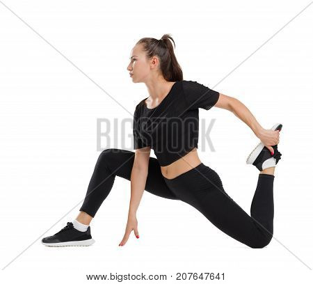 Young girl in black suit doing stretching exercises, isolated on white background.