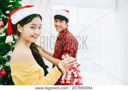 Young Asian teens are decorating the Christmas tree and party at their home. BCE to celebrate the coming 2018.