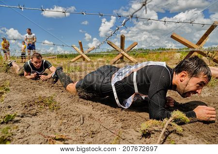 Tyumen, Russia - July 1, 2017: Race of Heroes project on the ground of the highest military and engineering school. People passing under a barbed wires or climbing obstacles