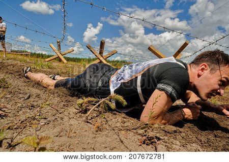 Tyumen, Russia - July 1, 2017: Race of Heroes project on the ground of the highest military and engineering school. People passing under a barbed wires or climbing obstacles