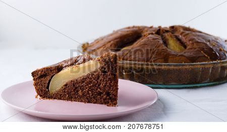 Slice of pear pie on pink plate with whole baked pie in background