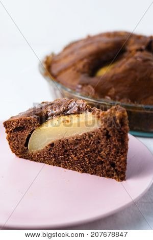 Slice of pear pie on pink plate with whole baked pie in background