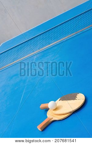old pingpong rackets and ball and net on a blue pingpong table