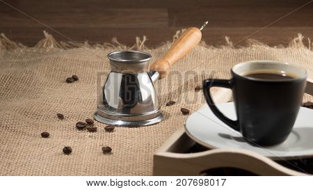 Coffee gezve. Coffee grains and cup of coffee in wooden box. Coffee cup. Coffee gezve and box on the sackcloth background. Brown image