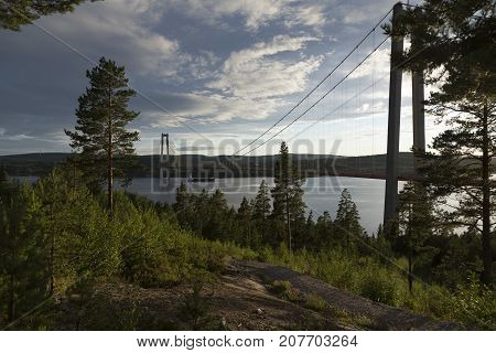 A bridge with a boat under it some clouds in the sky