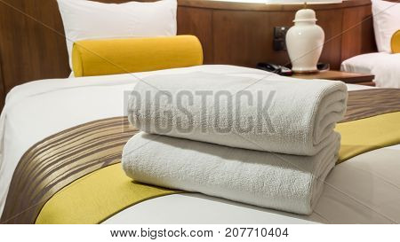 Two white laundered fluffy towels on white bed in bedroom interior at the hotel