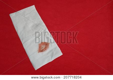 Reddish brown lipstick on napkin white and top table surface of leatherette texture for background