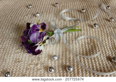 Still life with a pansy, a bouquet of flowers tied with ribbon and strewn with beads