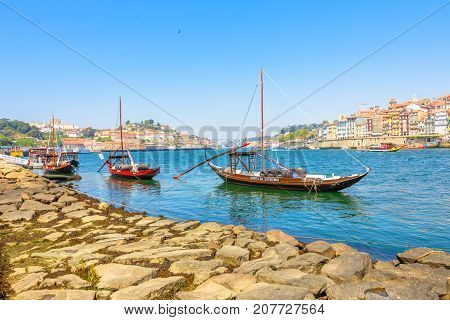 Porto, Portugal - August 13, 2017: Oporto waterfront with Ribeira skyline.A traditional Rabelo boat, used for transportation of port wine from Douro Valley region, to wine cellars in Vila Nova de Gaia