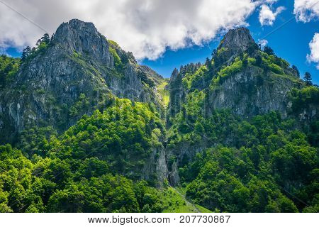 Scenic Green Meadow On The Background Of High Peaked Rocks.