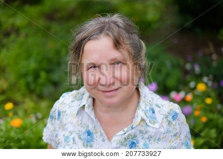 Portrait of caucasian mature cheerful mature woman standing outdoors in garden. She is smiling. View from top to bottom.