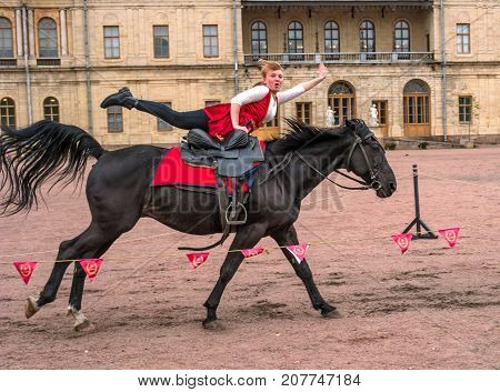 Gatchina St. Petersburg Russia - September 30 2017: Horse show of Cossacks on the parade ground of the Gatchina Palace. Young Cossack performs tricks on horseback.