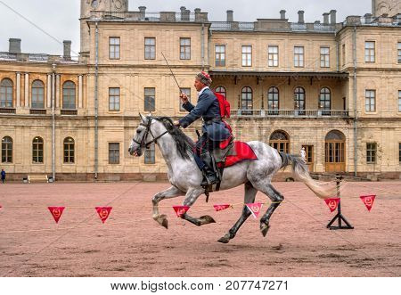 Gatchina St. Petersburg Russia - September 30 2017: Horse show of Cossacks on the parade ground of the Gatchina Palace. The Cossack is juggling a sword.