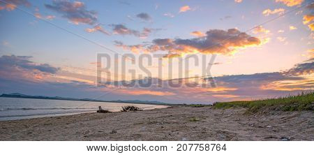 a beach on the sea, sand and waves, seagulls fly over the water. Sunset