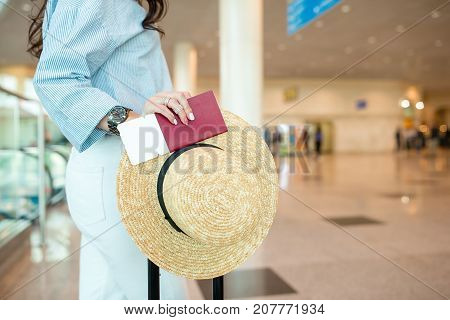 Closeup of woman holding passports and boarding pass at airport