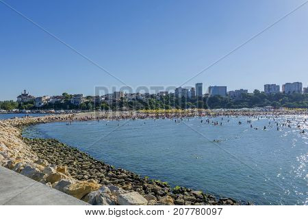 People on the beach, sunbathing and swimming, enjoying on vacation. Beach full of people on Modern Beach, Constanta,Romania. Black Sea coast - Constanta bay, panoramic view.