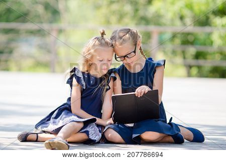 Adorable little school girls with notes and pencils outdoor.