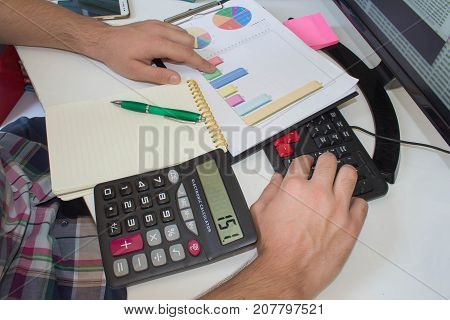 Businessman with computer at the deskdiscussing the charts and graphs showing the results of their successful teamwork. businessman working at a computer hands closeup