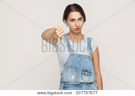 Young Adult Woman Showing Thumb Down Isolated On A Gray Background. .