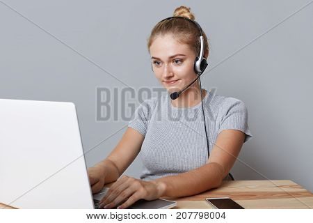 Young Female Operator Or Consulatant Has Headphones, Looks At Laptop Computer, Makes Video Calls, Us