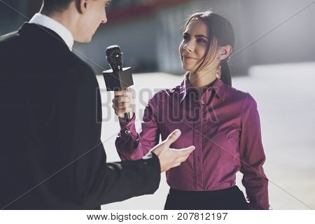 TV reporter at work. On a clear day, a girl interviews a man in a suit