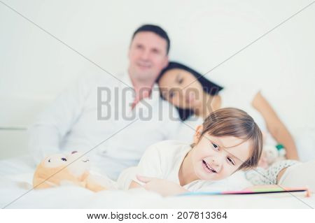 Father Mother Brothers and sister read a bedtime story togather on the bed in bedroom kid child family study education and home work concept
