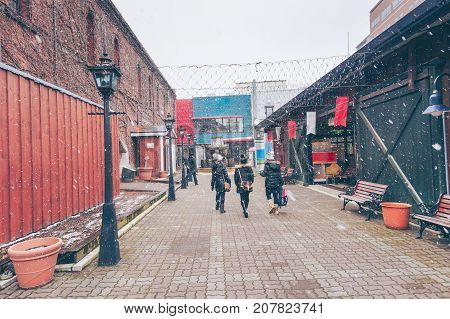 Traveler walking with happinest into the historic Red Brick Warehouses with snow in winter season at Hakodate Hokkaido Japan