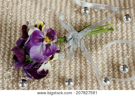 Still life with a pansy a bouquet of flowers tied with ribbon and strewn with beads
