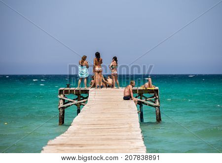 Alcudia, Majorca, Balearic islands, July 2017: Tourists enjoy Alcudia bay sea view from a wooden jetty