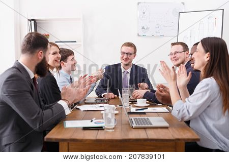 Emploees clapping hands cheering successful reporter, friendly atmosphere. Communication with partners at the desk