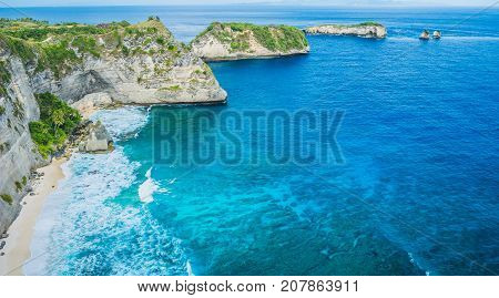 Rock in the ocean with beautiful palms behind at Atuh beach on Nusa Penida island, Indonesia.