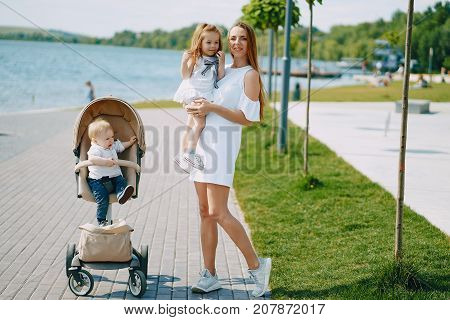 a beautiful young long-haired mom in the park with her beautiful little son and charming daughter