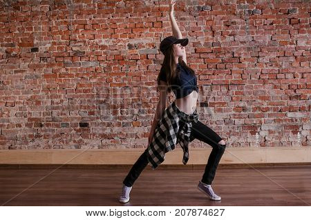 Dance is life. Hip hop lifestyle. Happiness in moving, sporty teenage girl on brick wall background with free space. Flexible dancing young female, breakdance concept