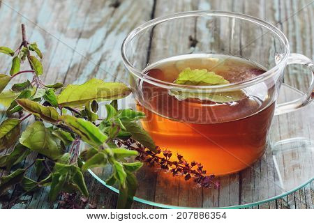 Tulsi Tea served in a cup with fresh leaves on the side selective focus