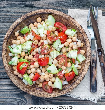 Chickpeas salad with cherry tomatoes cucumbers basil and onion with citrus dressing top view square format