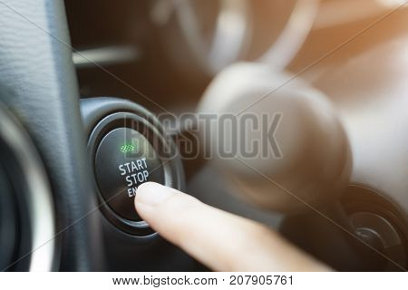 Close up of finger pressing the start/stop engine button on car.