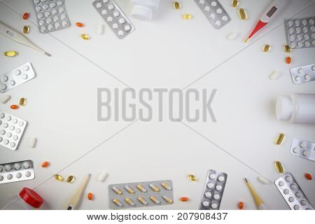 Pills border background. Vitamins, pills in blister pack drug tablets, bottles, thermometers on white background. Top view.