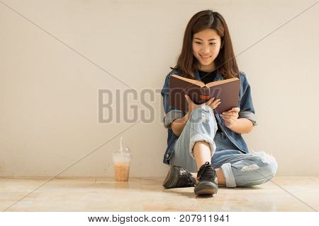 Asian woman reading a book with vintage clothing jeans style old background.