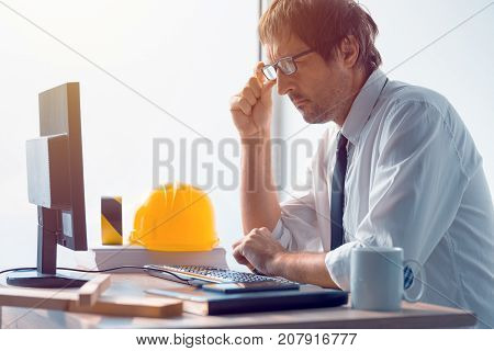 Construction engineer working on desktop computer using CAD software to sketch project in architecture studio office