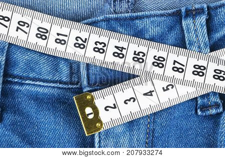 A blue woman jeans and ruler concept of diet and weight loss. Jeans with measuring tape. Healthy lifestyle dieting fitness. Weight control. Successful diet. Reducing excess weight