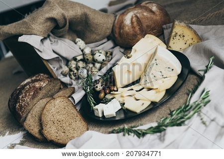 Cooking delicious sandwiches for breakfast. Making meal with herbs, cheeses, bread and other tasty food. Beige colours and warm atmosphere of a calm village day