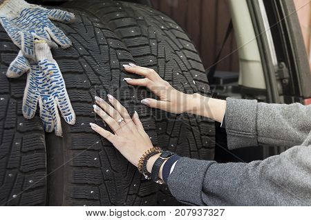 Manicured female hands pushing winter tyres into a car boot cropped outdoor shot